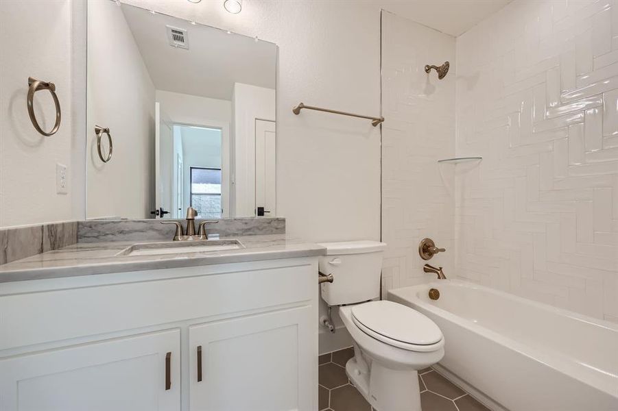 Full bathroom featuring tiled shower / bath combo, vanity, toilet, and tile patterned flooring