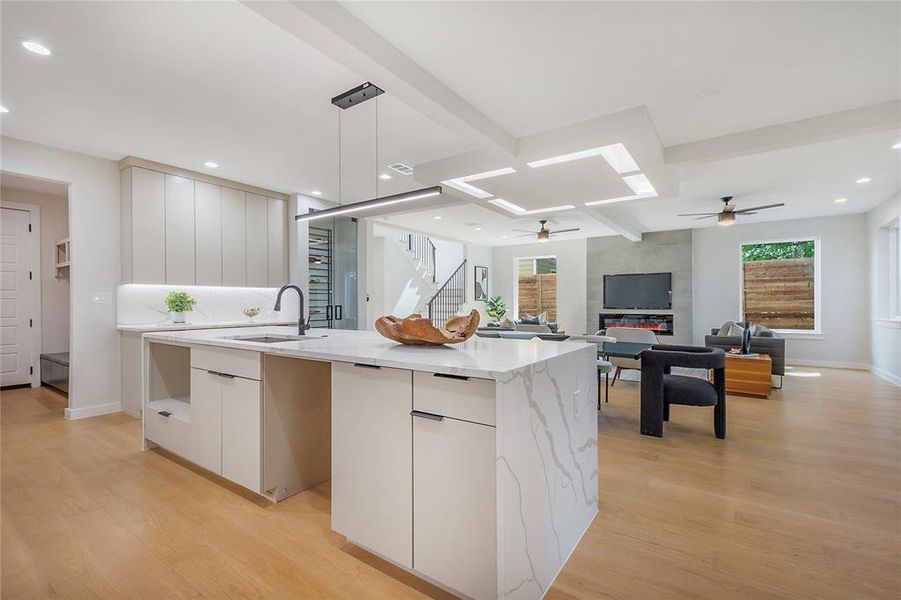 Kitchen with white cabinetry, light hardwood / wood-style floors, an island with sink, and ceiling fan