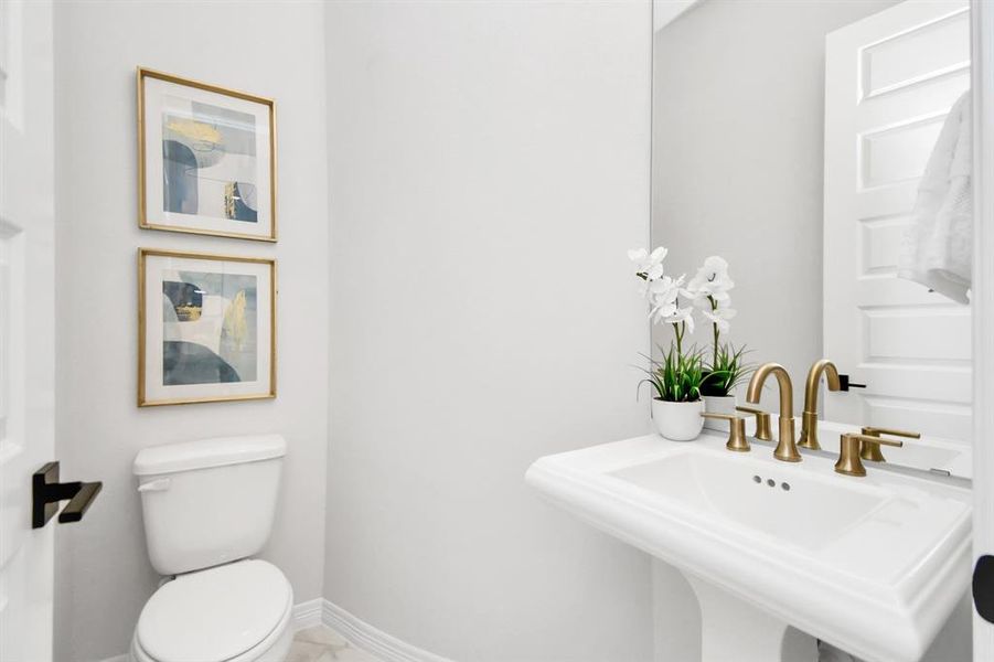 The half bathroom features a modern pedestal sink.