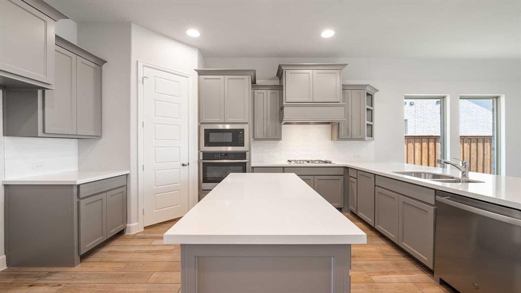 Kitchen featuring decorative backsplash, gray cabinets, and appliances with stainless steel finishes