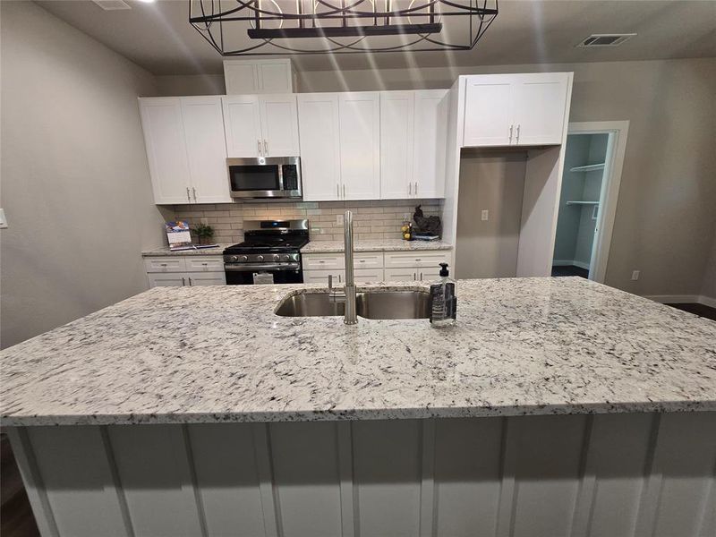 Kitchen featuring white cabinets, appliances with stainless steel finishes, sink, and tasteful backsplash