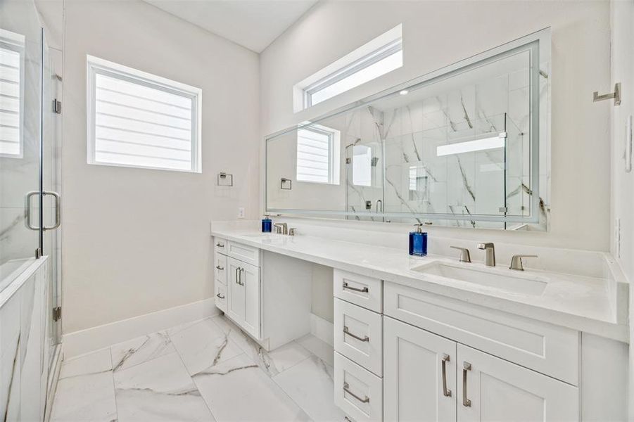 Luxurious primary bathroom has large backlit mirror and a double sink.