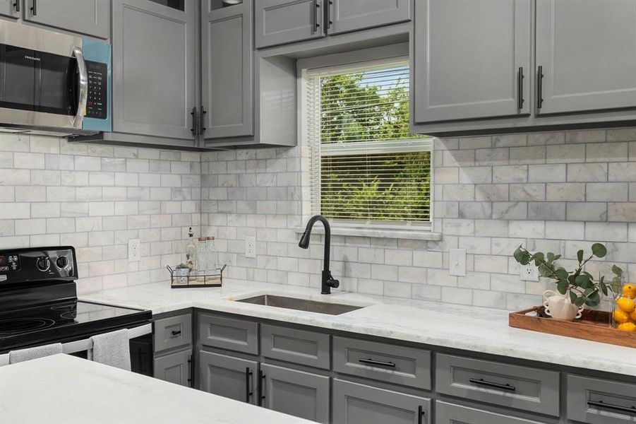 Kitchen featuring tasteful backsplash, light stone counters, electric stove, gray cabinets, and sink