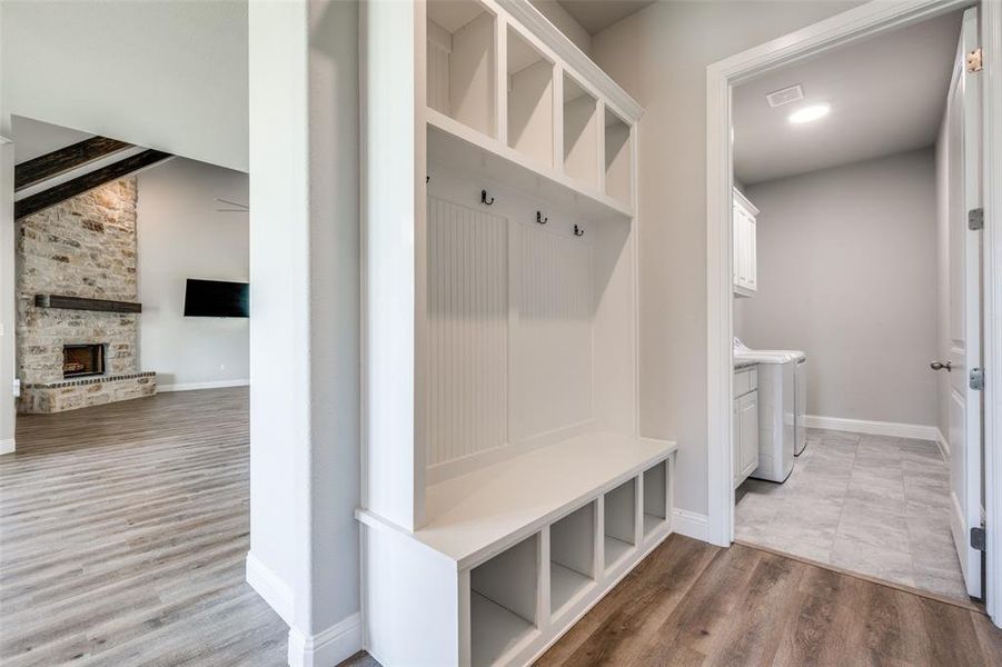 Mudroom featuring a stone fireplace, independent washer and dryer, and hardwood / wood-style floors