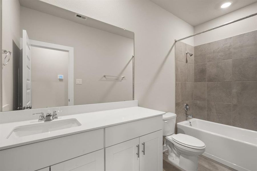 Second floor bathroom offers sleek countertop, built-in cabinetry and tub/shower combo with tile surround.