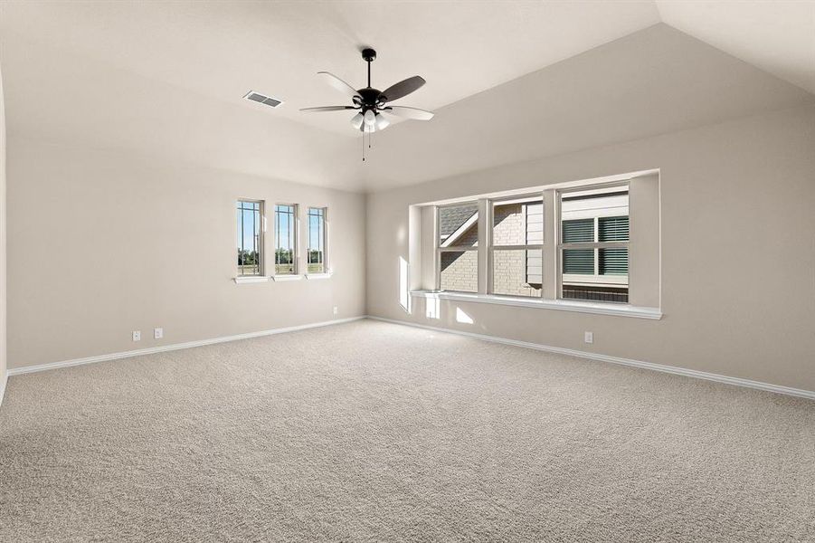 Carpeted empty room with ceiling fan and vaulted ceiling