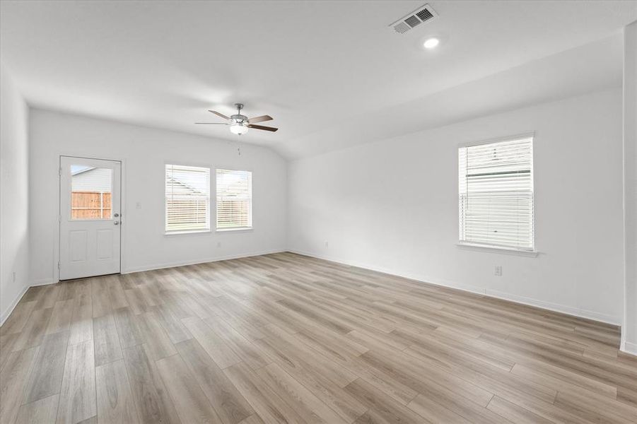 Empty room featuring ceiling fan, lofted ceiling, and light hardwood / wood-style floors