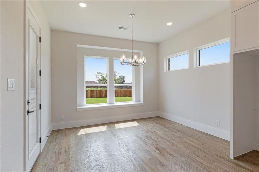 Unfurnished room featuring a chandelier and light hardwood / wood-style flooring