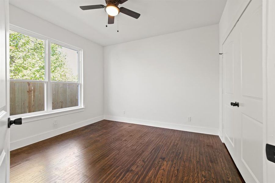 Empty room featuring ceiling fan and dark hardwood / wood-style flooring