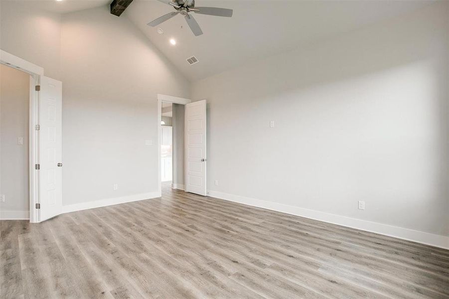 Spare room with high vaulted ceiling, beam ceiling, ceiling fan, and light wood-type flooring