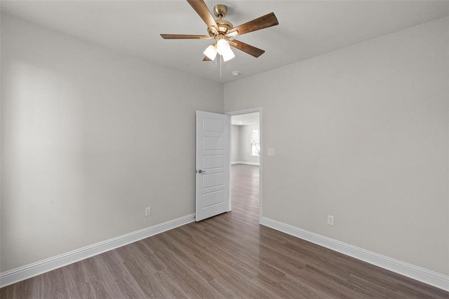 Unfurnished room with dark wood-type flooring and ceiling fan