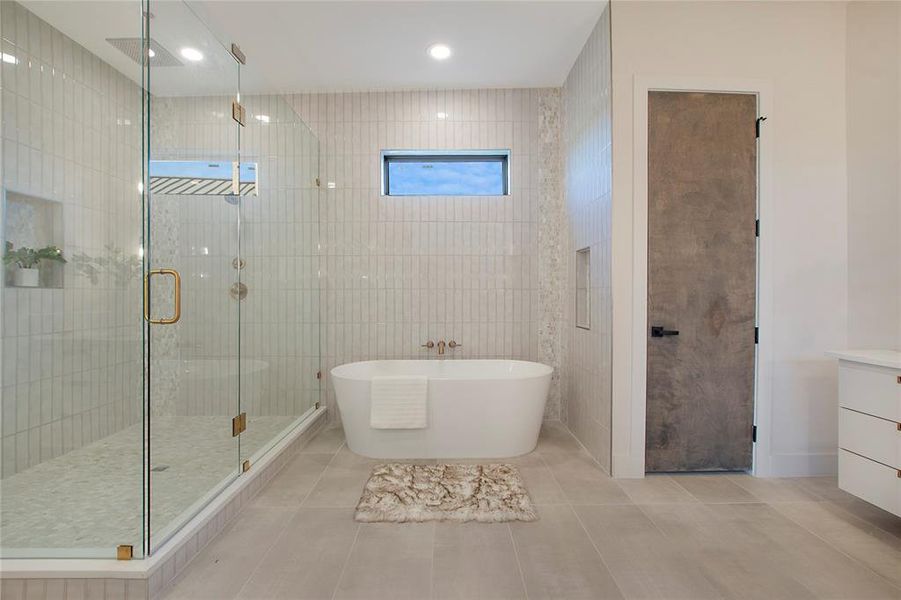 Bathroom featuring tile patterned flooring, tile walls, independent shower and bath, and vanity