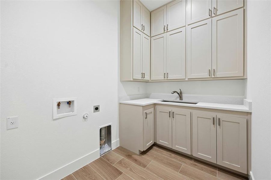 Very spacious laundry room with ample storage, quartz countertops, and sink.