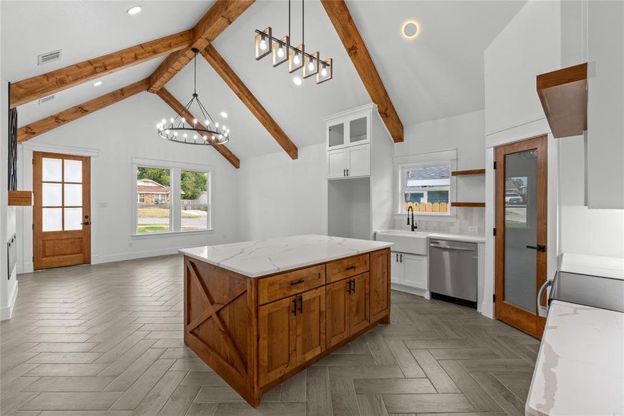 Kitchen featuring white cabinets, beam ceiling, a kitchen island, stainless steel dishwasher, and sink