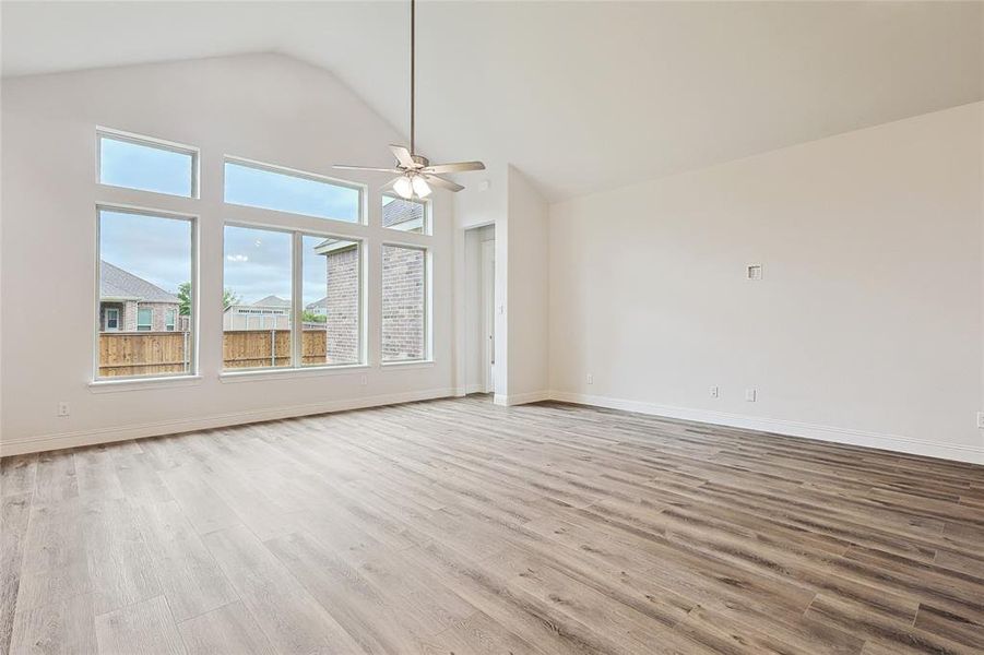 Empty room featuring ceiling fan, light wood-type flooring, and high vaulted ceiling