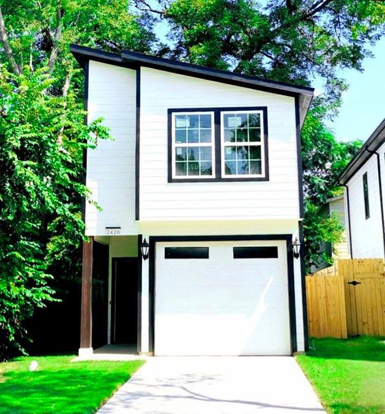 View of front of property with a garage and a front lawn