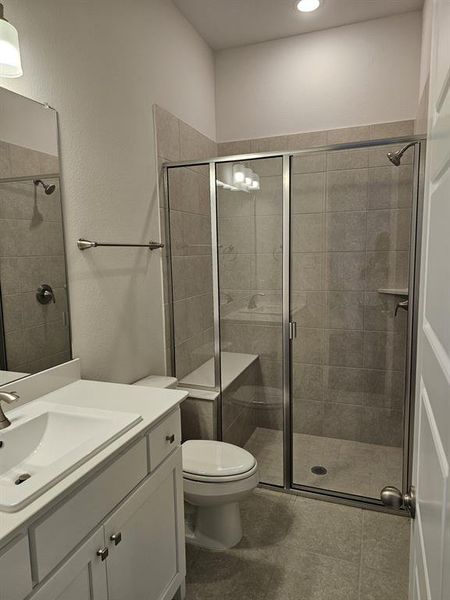 Bathroom with tile floors, an enclosed shower, toilet, and oversized vanity