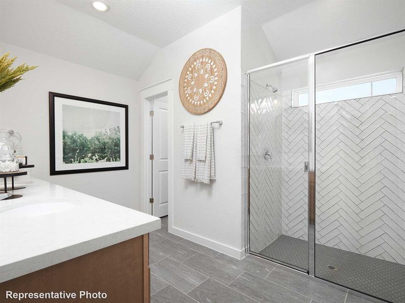 Bathroom featuring a shower with door, vanity, tile patterned flooring, and lofted ceiling
