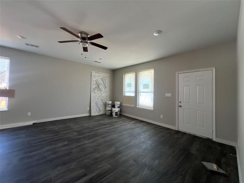 Unfurnished room with a wealth of natural light, ceiling fan, and dark wood-type flooring