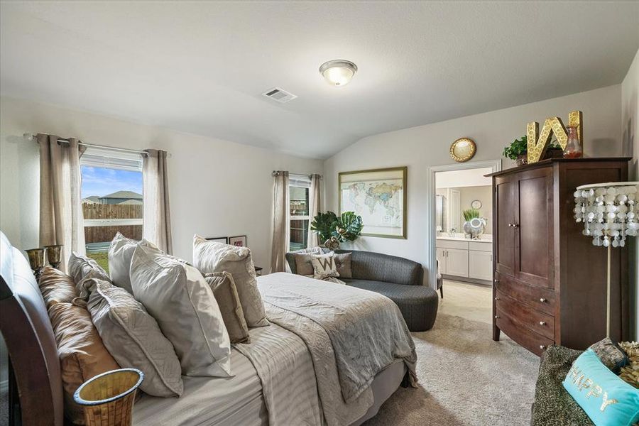 Carpeted bedroom with lofted ceiling and ensuite bathroom.