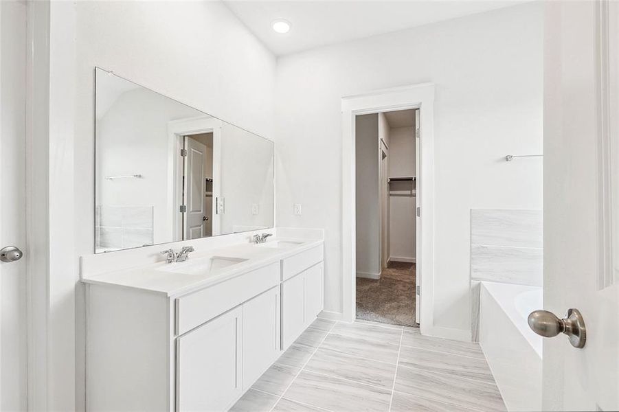 Bathroom with dual vanity, tile patterned flooring, and a tub