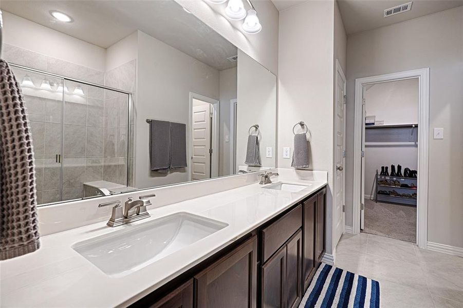 Primary bathroom with dual sinks, stained cabinets and extra linen closet