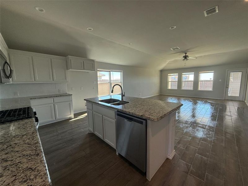 Kitchen with dishwasher, white cabinets, vaulted ceiling, and sink