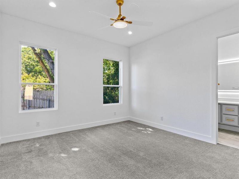 Carpeted spare room with ceiling fan and plenty of natural light