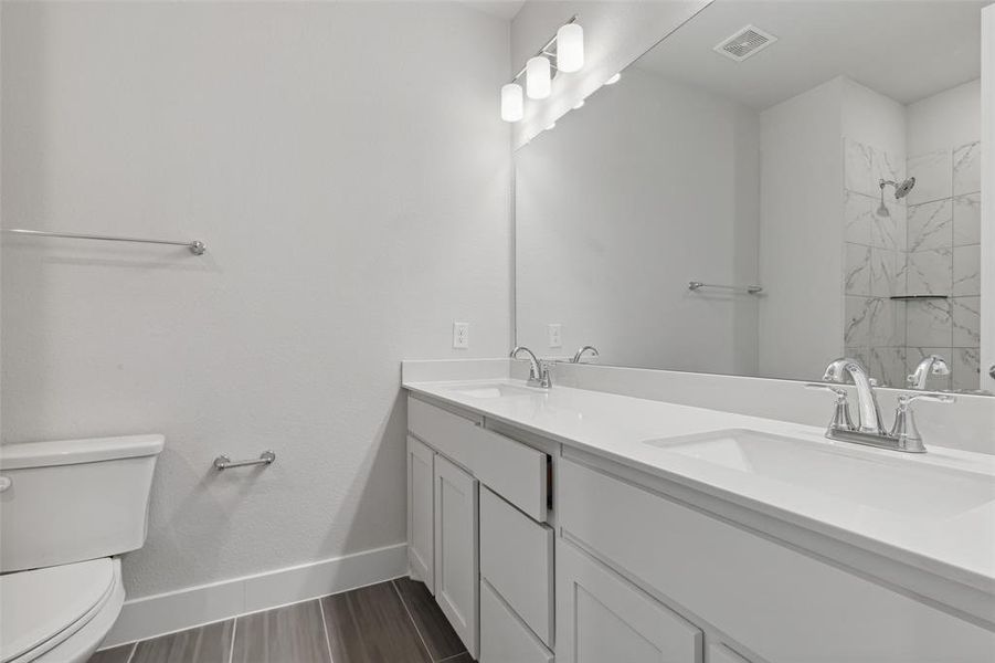 Bathroom featuring double vanity, toilet, and tile floors