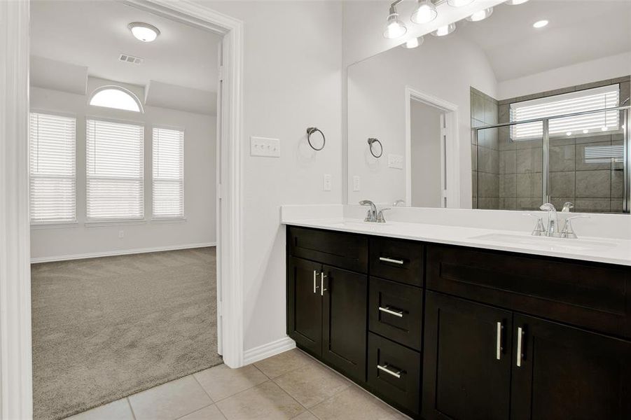 Bathroom with tile flooring, plenty of natural light, and dual bowl vanity