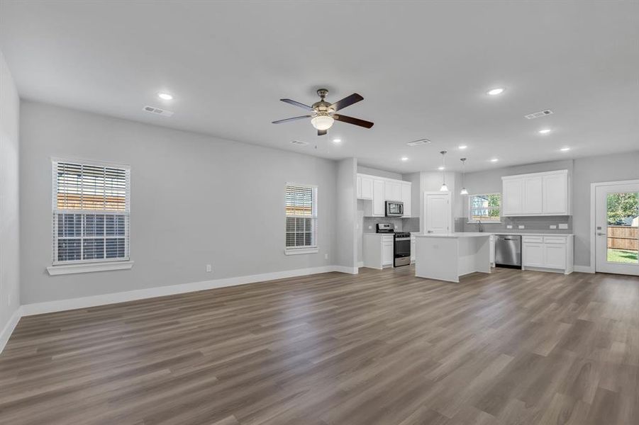 Unfurnished living room with ceiling fan and hardwood / wood-style floors