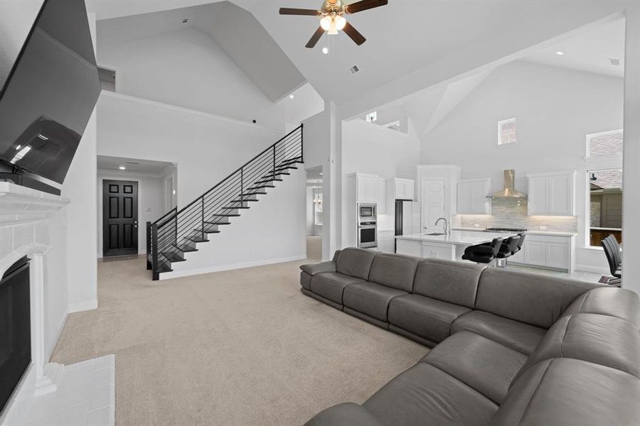 Living room with high vaulted ceiling, sink, ceiling fan, and light colored carpet