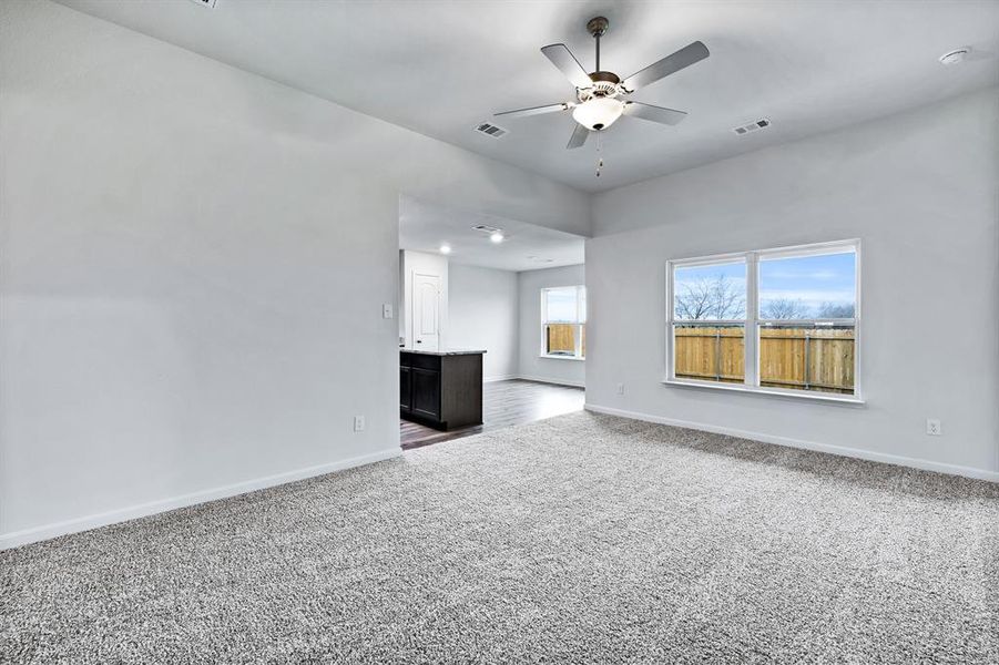 Unfurnished living room featuring carpet floors and ceiling fan