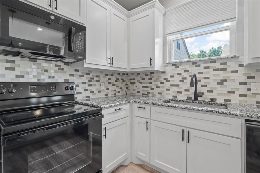 Kitchen with white cabinetry, tasteful backsplash, and black appliances