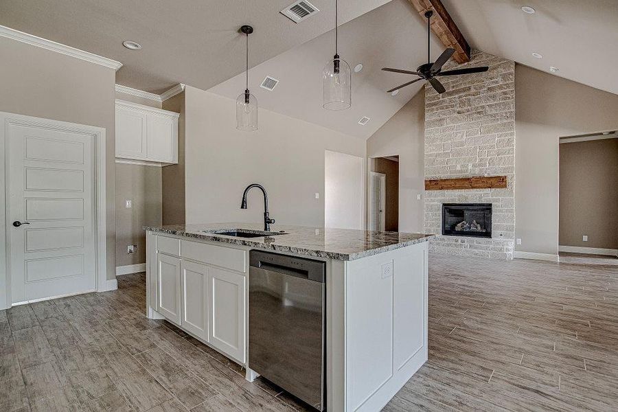 Kitchen with beamed ceiling, white cabinets, sink, stainless steel dishwasher, and ceiling fan