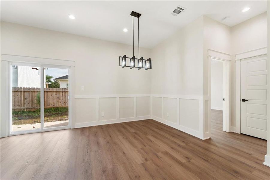 The spacious dining area is highlighted by a modern chandelier and custom trim accents.