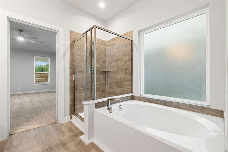 Enjoy the roomy walk-in shower encased in stylish tile, take a moment to unwind in a separate garden tub embellished with custom details. Sample photo of completed home with similar floor plan. As-built interior colors and selections may vary.