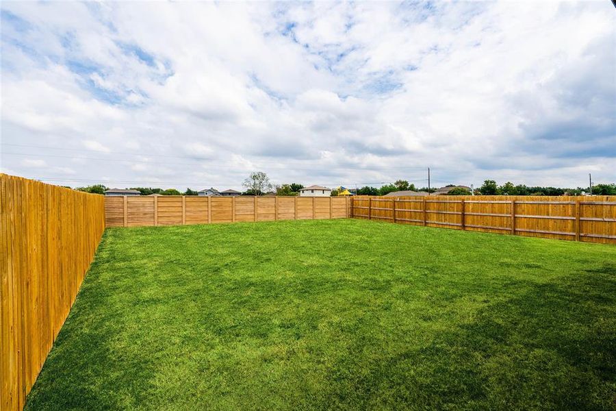 Large, lush backyard with privacy fence