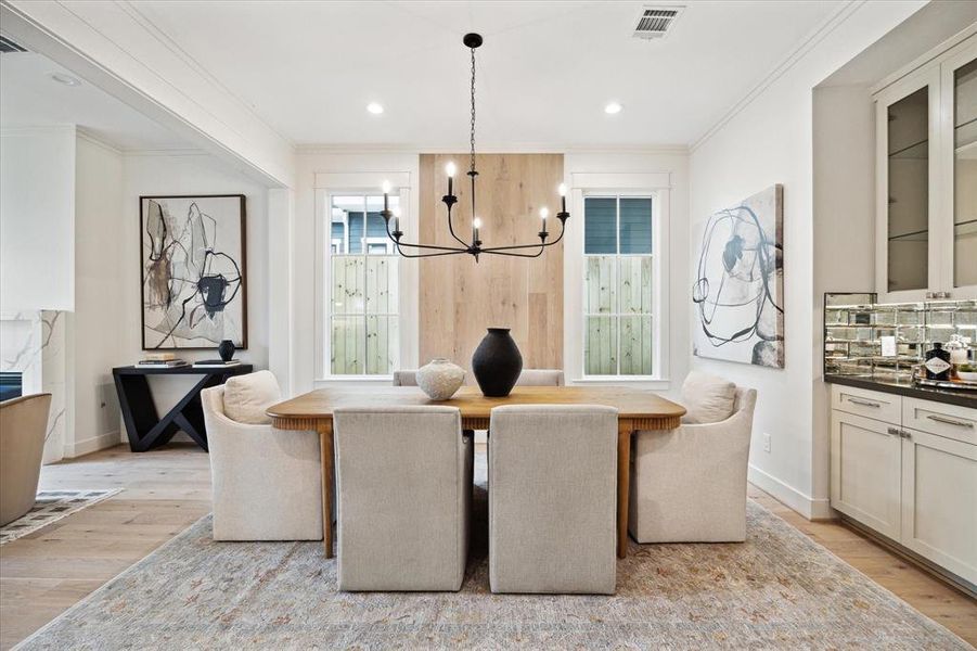 The dining room is perfectly situated to provide a formal space that is also open to the living area for ease of flow when entertaining. The bar area features mirrored tile backsplash for a touch of glamour, lower cabinets for storage and upper cabinets for displaying glassware. Additionally there a wood feature wall to add some warmth and texture to the space.