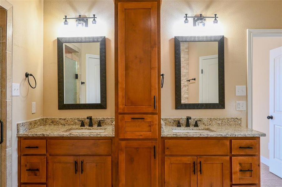 His and hers sinks and cabinets with granite countertops and custom mirrors and lighting.