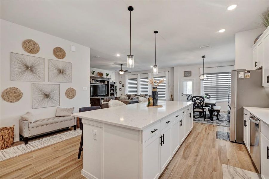 Bright and Airy Kitchen - Additional seating on the far left wall, ample space between the island and kitchen sink, and lovely natural lighting, creating a bright and airy atmosphere.