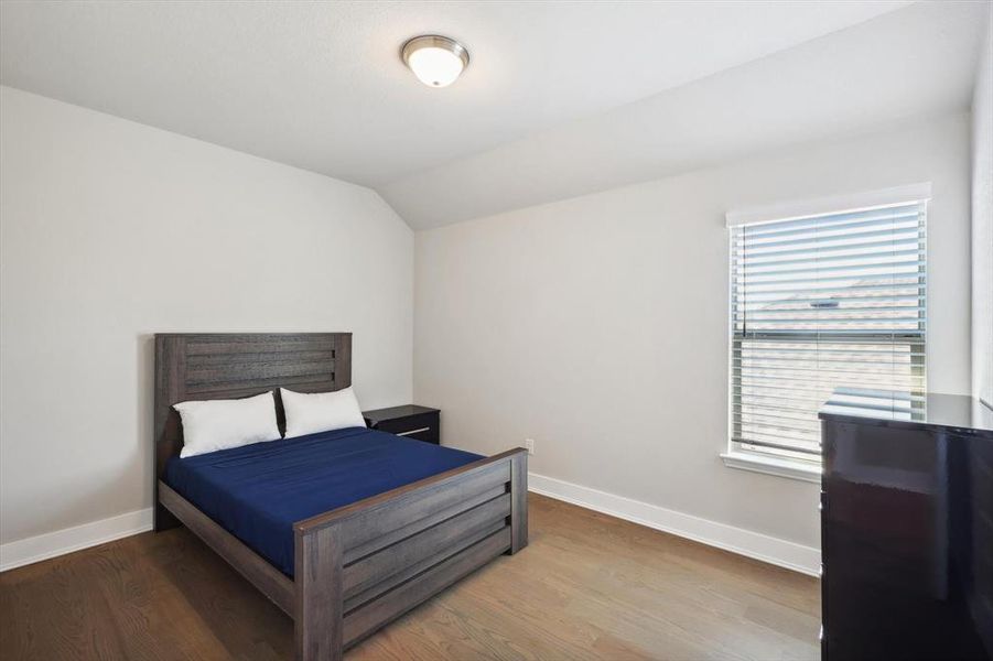 Bedroom with hardwood / wood-style flooring and vaulted ceiling