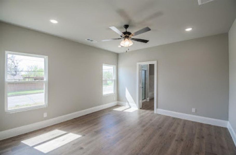 Empty room featuring plenty of natural light, ceiling fan, and hardwood / wood-style flooring