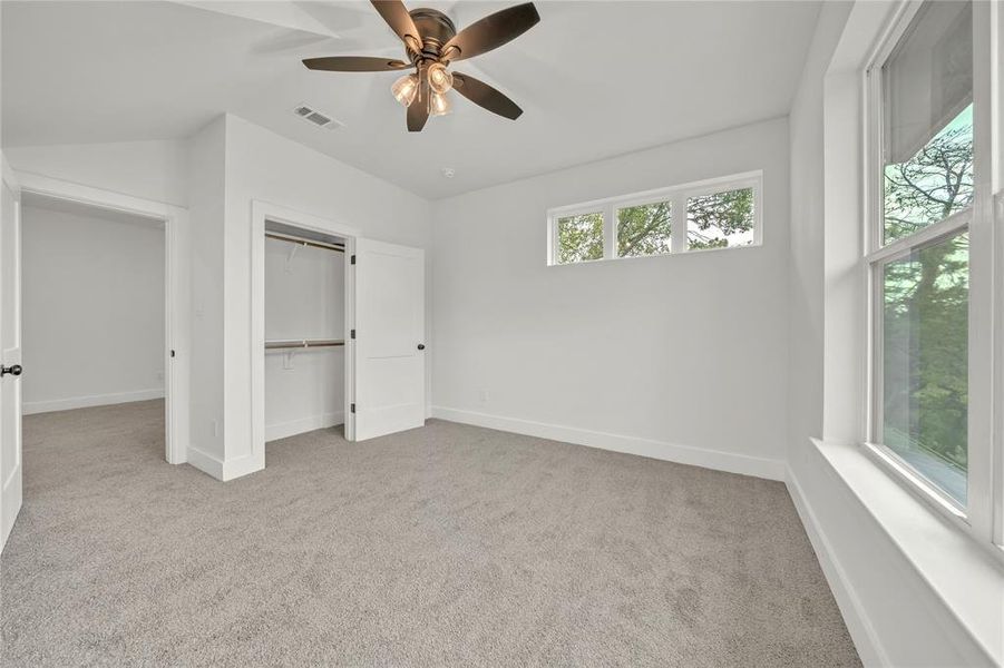Unfurnished bedroom featuring light colored carpet, a closet, ceiling fan, and vaulted ceiling