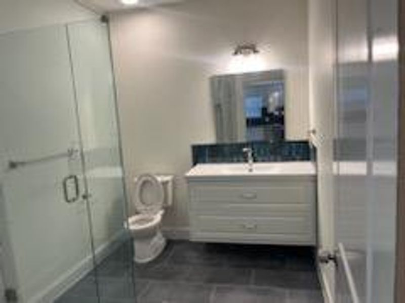 Bathroom with vanity, toilet, walk in shower, and tile patterned floors