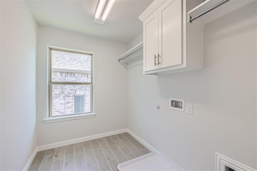 Laundry area featuring washer hookup, wood-type flooring, cabinets, and hookup for a gas dryer