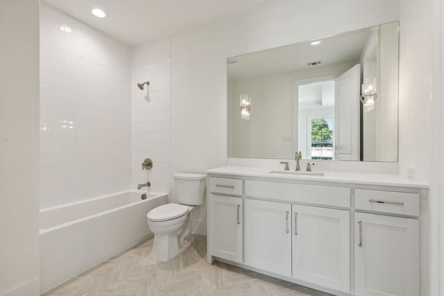 Full bathroom with tiled shower / bath, vanity, and toilet