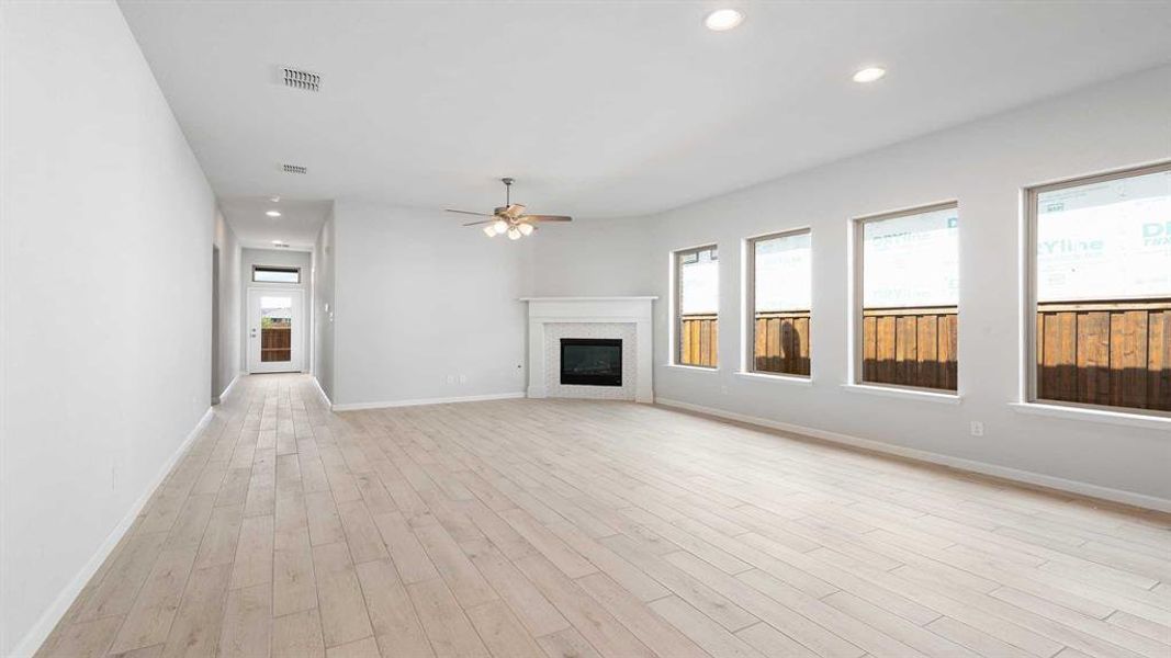 Unfurnished living room with ceiling fan, light wood-type flooring, and plenty of natural light