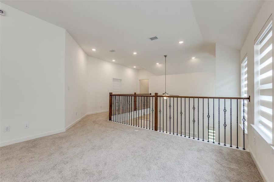 Spare room with a healthy amount of sunlight, light colored carpet, and vaulted ceiling