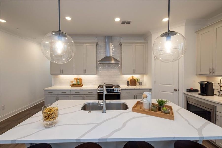 Kitchen featuring appliances with stainless steel finishes, wall chimney range hood, decorative backsplash, dark hardwood / wood-style floors, and a kitchen island with sink , not the actual unit (Model Home )